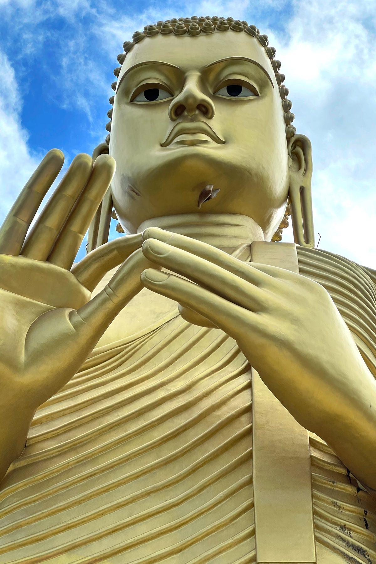 A giant golden Lord Buddha statue against a blue sky