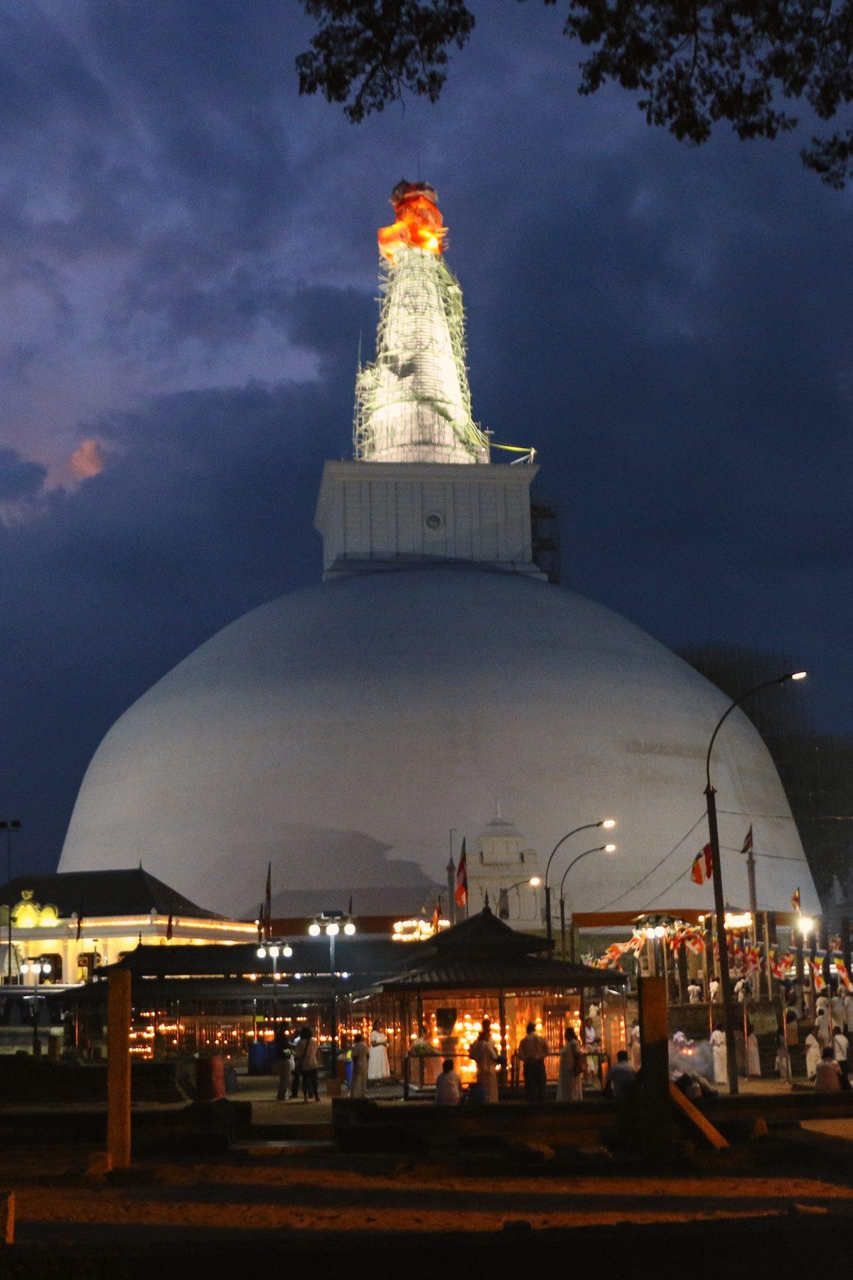 Mahaseya stupa lit up at night under a stormy sky