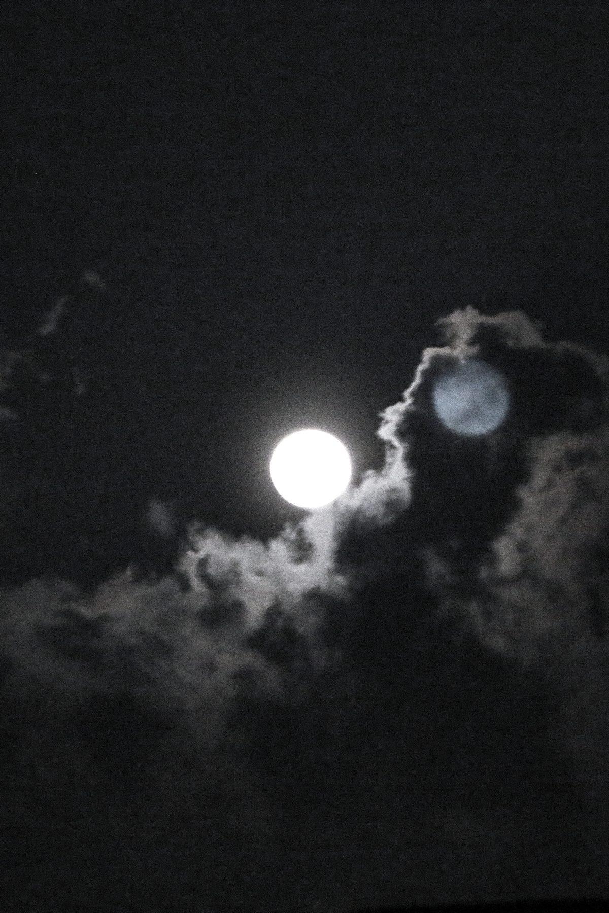 The moon behind drifting clouds at night